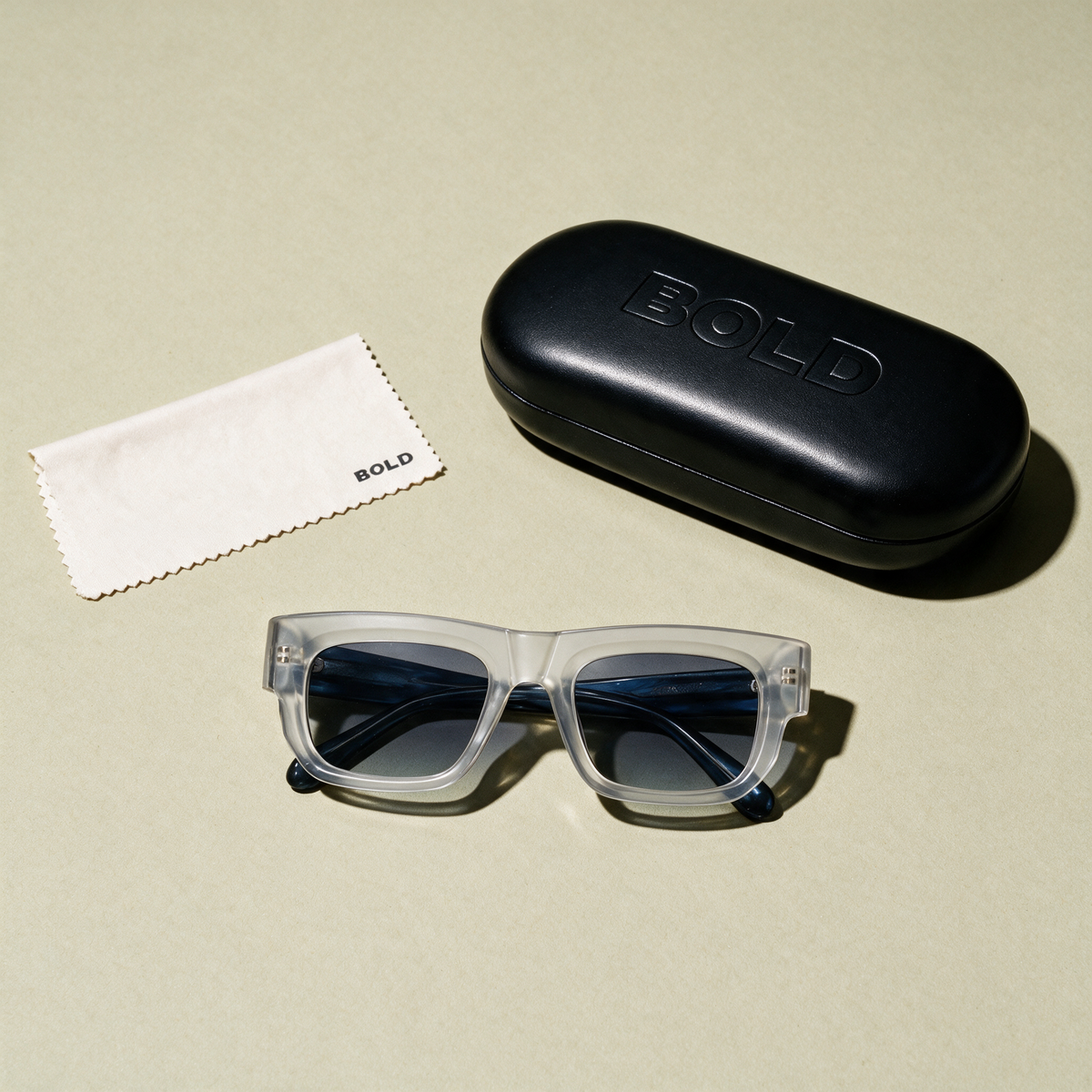 CHISEL Frame 22 sunglasses in GLACIER, flat lay with BOLD hard case and cleaning cloth